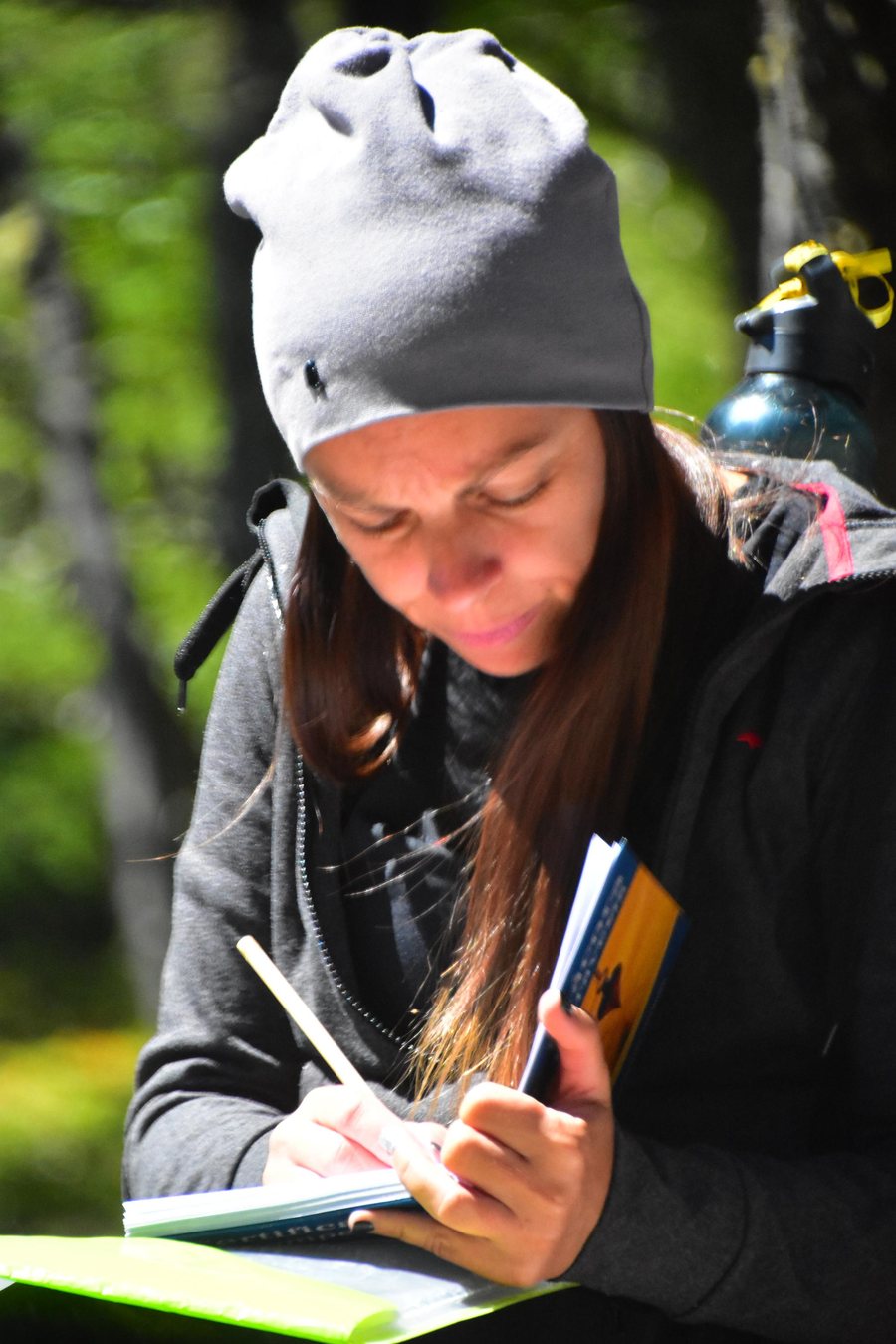 Mujer escribiendo en su cuaderno durante una travesía en el bosque